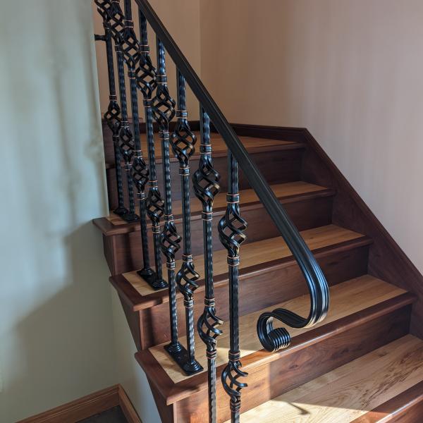 Black railing with copper embellishments attached to a staircase