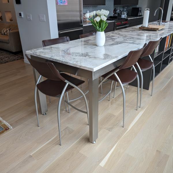 Stainless steel table with a marble tabletop.  Brown stainless steel chairs are nestled under the table.