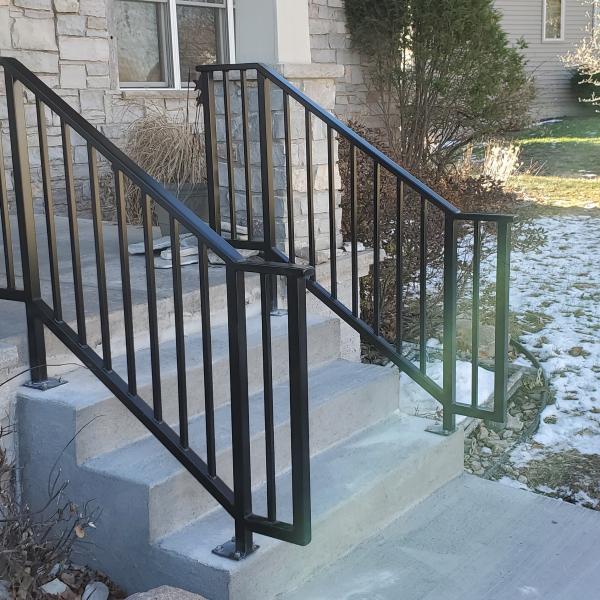 Two black modern craftsman railings sit on both sides of this stoop. 