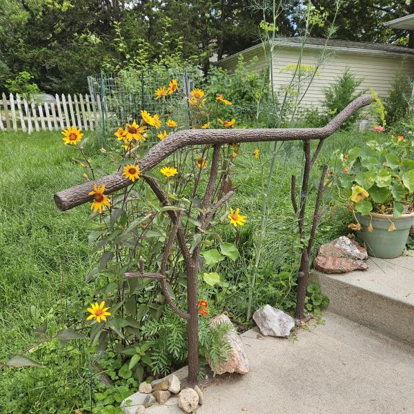 A tree branch railing with flowers around it