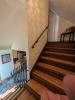 Panoramic view of the staircase with picketed railing and grab rail down the left hand side of a wall