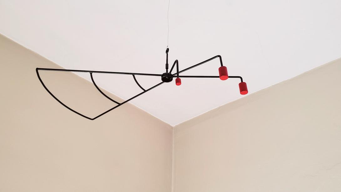 Orthographic view of a modern hanging sculpture.  1/4" round steel is bent to look similar to a wing or fan on one side of this sculpture while 3 red steel slugs counter balance the other side.  Painted black round and painted red steel slugs.