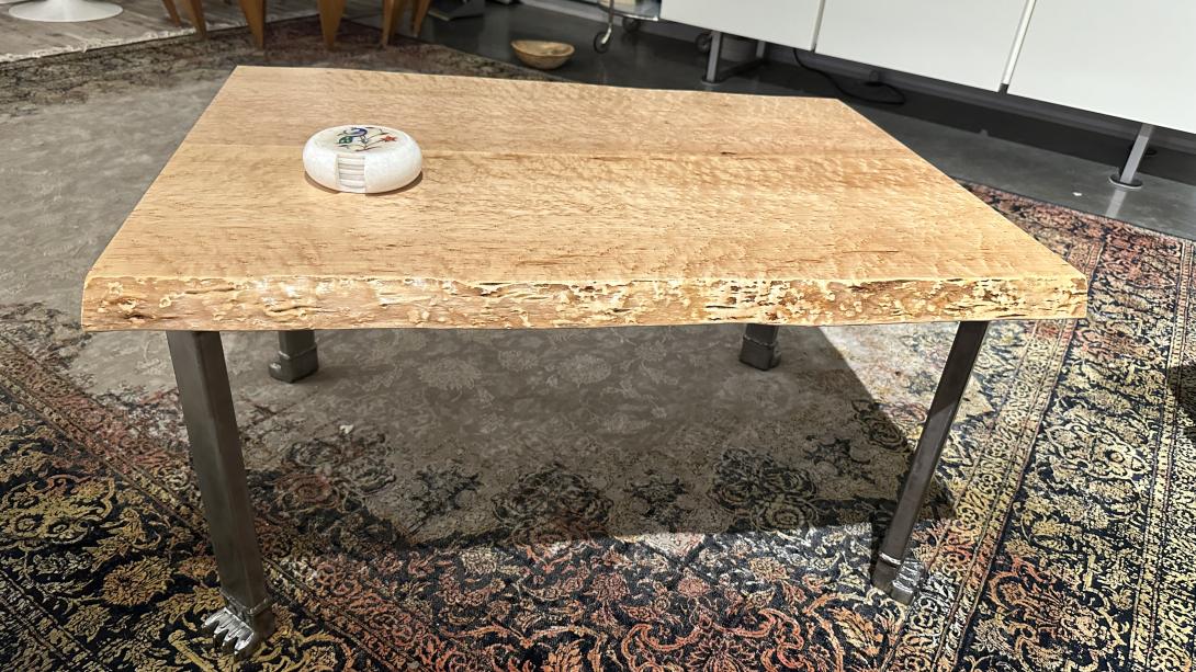 Bird's eye maple table top sit on a steel table frame with sculpted lion paw feet