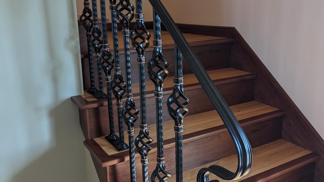 Black railing with copper embellishments attached to a staircase