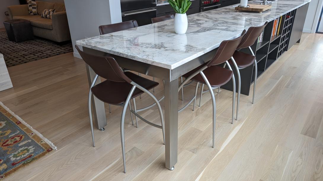 Stainless steel table with a marble tabletop.  Brown stainless steel chairs are nestled under the table.