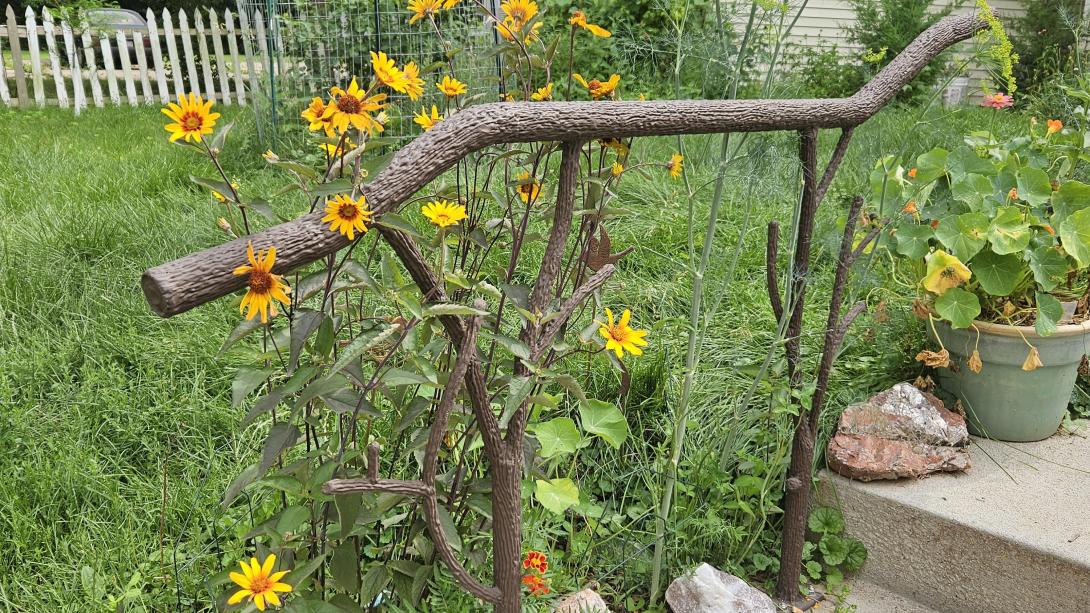 A tree branch railing with flowers around it